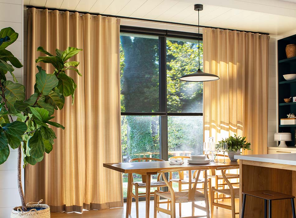 A bright, sunlit dining room featuring Dashing Stripe in Palomino Cubicle Drapery used as a sliding glass door curtain.