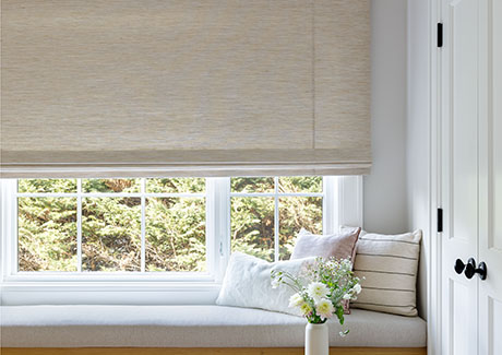 One of the trending window treatment styles is the use of natural fibers seen on these Flat Roman Shades in a bedroom