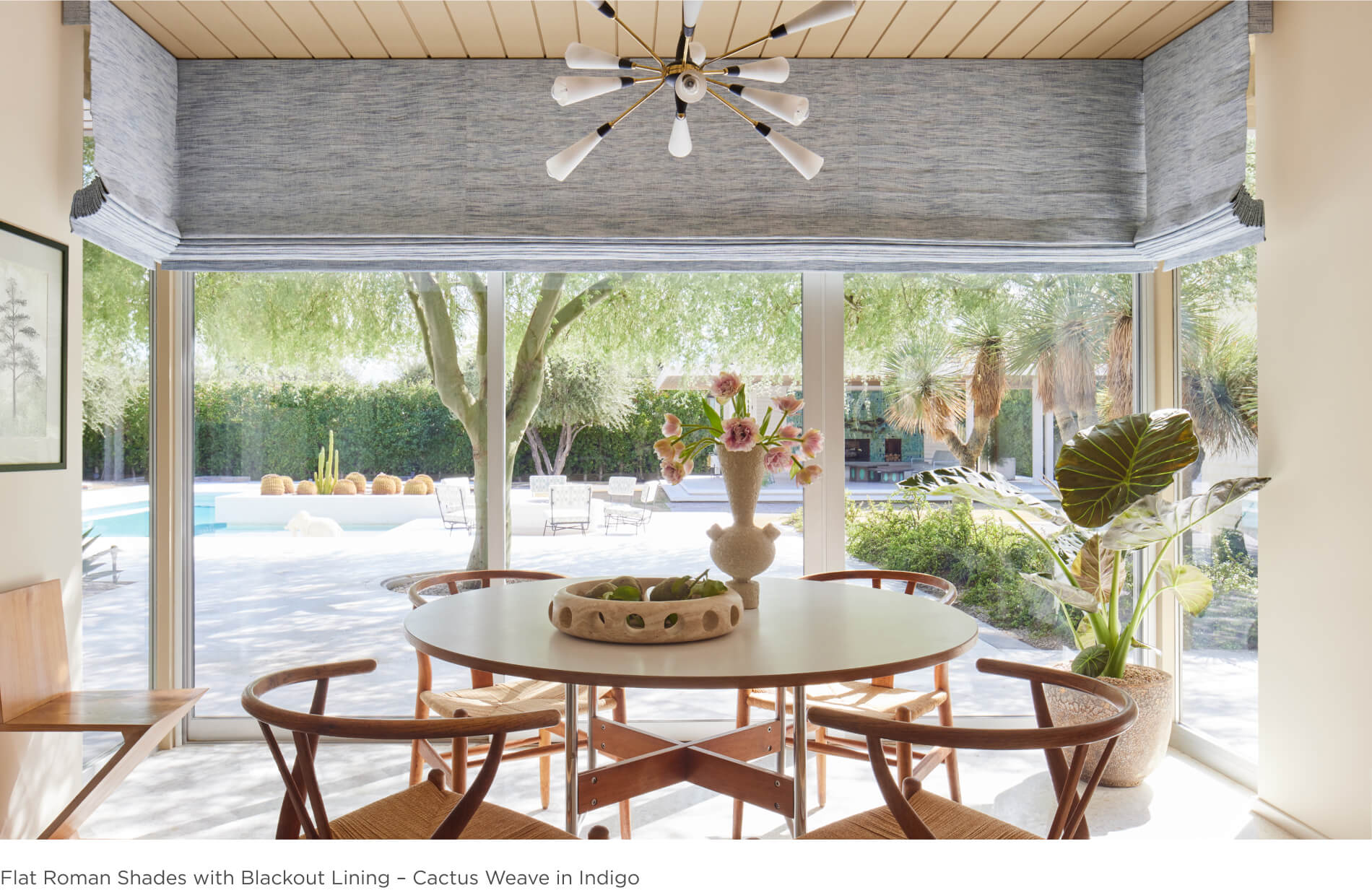 A dining room with table and chairs features flat roman shades made of Martyn Lawrence Bullard's Cactus Weave in Indigo