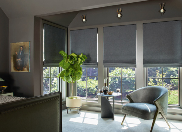 Bedroom with dark walls and furniture featuring Flat Roman Shades in material Wool Sateen and color Grey on large windows