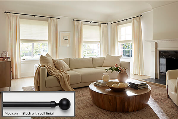One of the popular window treatments of 2026 is seen in this living room is high contrast hardware in black with white drapery