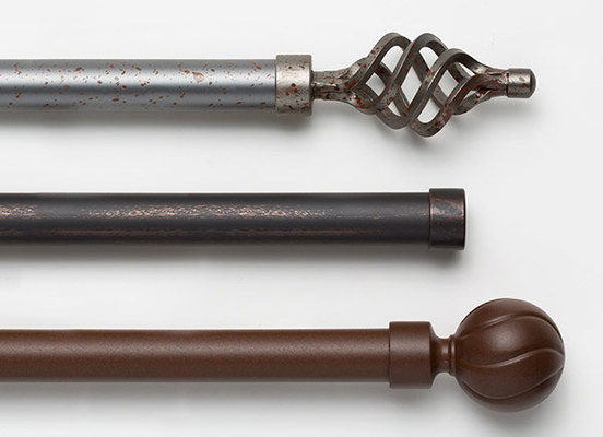 Three drapery hardware options in various Wrought Iron finishes laid out on a white table top