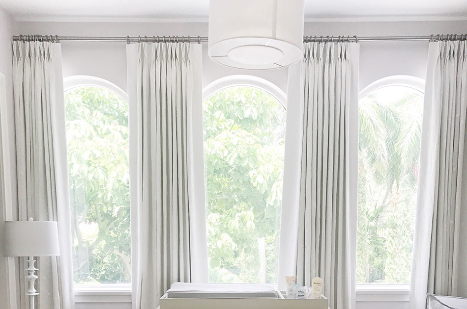 Light-filled room with curtains for arch windows and soft white drapery panelsā