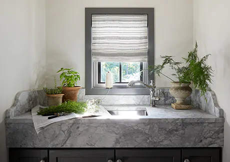 A laundry room features privacy shades in the Flat Roman Shade Style made of Tidal Line in Slate with privacy lining as functional window treatments for everyday privacy