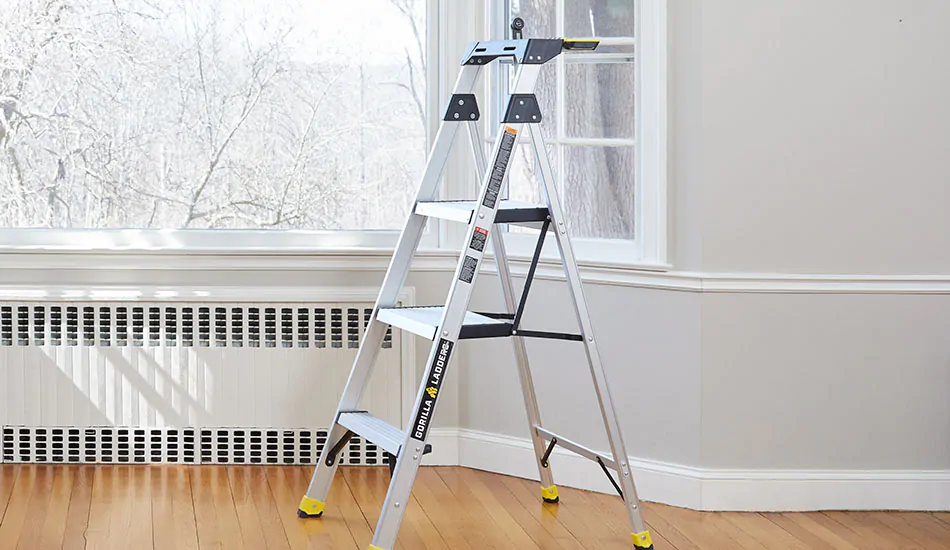 A step ladder sits in front of a bay window in preparation for the first step of how to measure for curtains: gathering tools