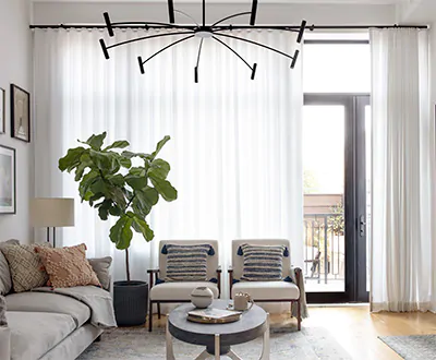 Modern window drapes in a living room include white sheer ripple fold drapery with a contrasting black curtain rod