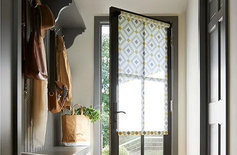 Front door window coverings with patterned Roman Shades on a glass entry door.