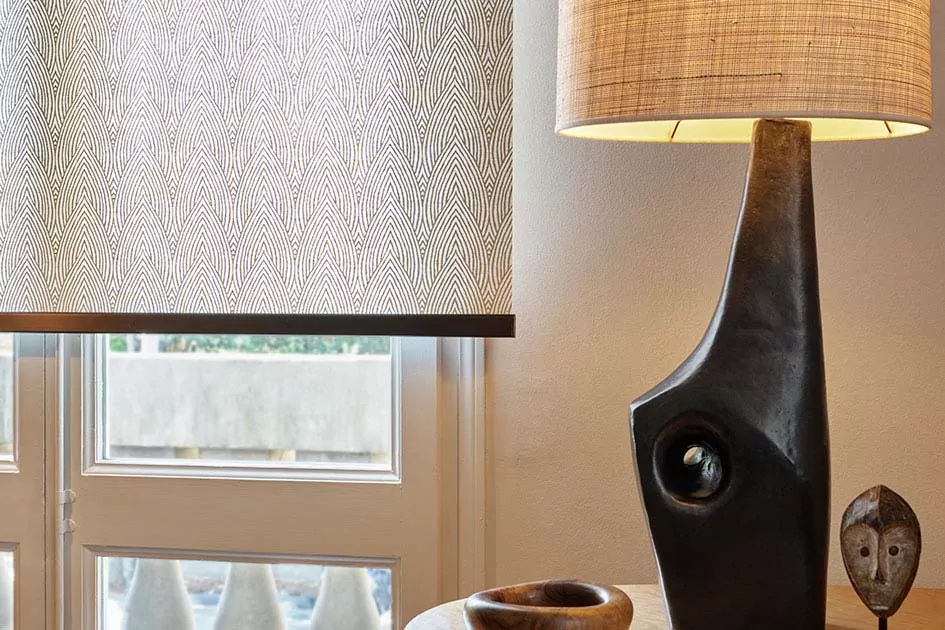 Mid century modern window treatments include a sleek roller shade with a tea leaf pattern and eclectic decor