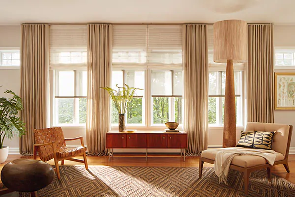 A warm inviting room has beige tones through layers of transitional window treatments including Drapery, Roman Shades and Solar Shades