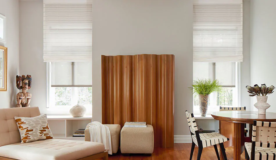 Modern solar shades layered with striped Flat Roman Shades in a Scandinavian-inspired room, filtering natural light to create a warm, clean, and cozy look.